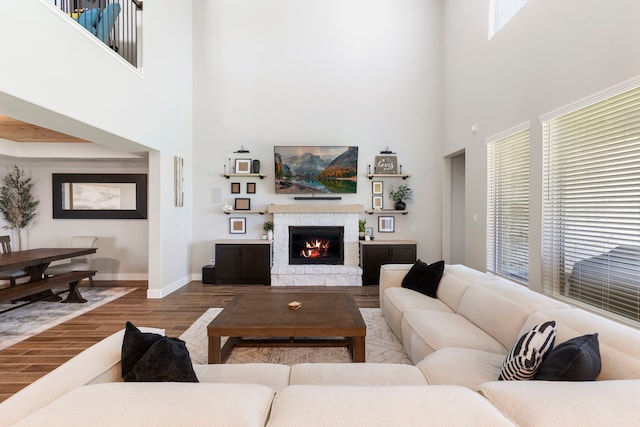 living room featuring a stone fireplace, wood finished floors, and baseboards