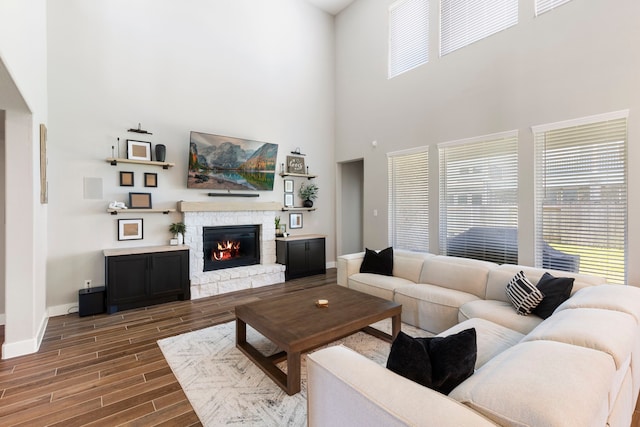 living room featuring plenty of natural light, a fireplace, baseboards, and wood finish floors