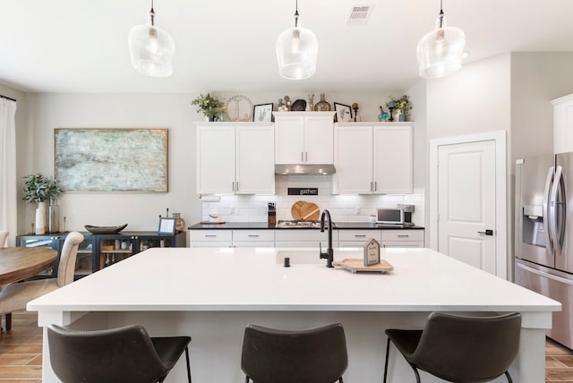 kitchen with under cabinet range hood, stainless steel appliances, and decorative light fixtures