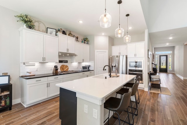 kitchen featuring appliances with stainless steel finishes, dark countertops, a sink, and white cabinets