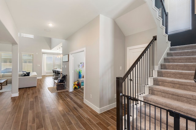 interior space with dark wood-style flooring, visible vents, stairway, a high ceiling, and baseboards