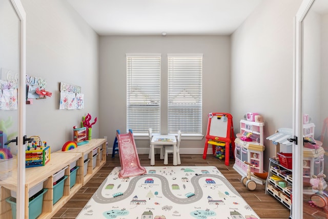 recreation room featuring a healthy amount of sunlight, wood tiled floor, and baseboards