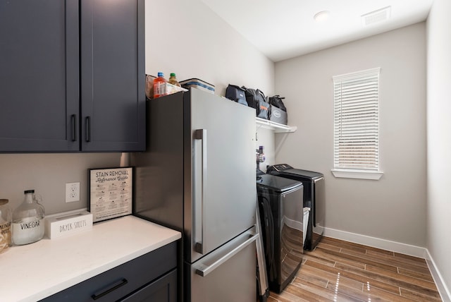 washroom featuring visible vents, cabinet space, light wood-style flooring, independent washer and dryer, and baseboards