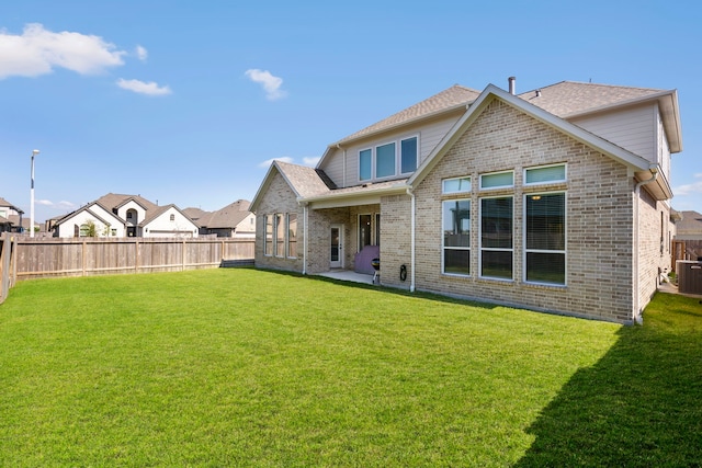 rear view of house with cooling unit, brick siding, fence, a lawn, and a residential view