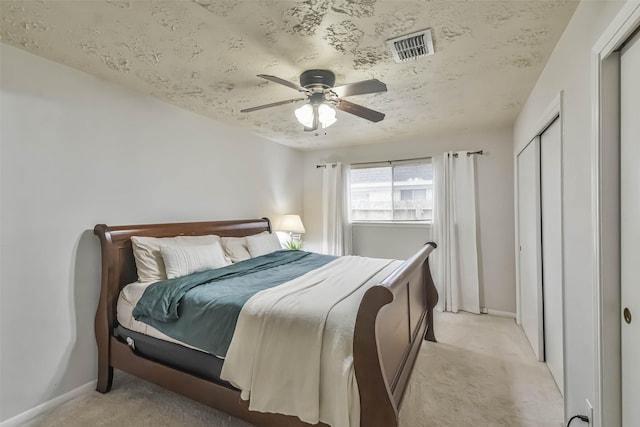 bedroom featuring visible vents, baseboards, light colored carpet, ceiling fan, and a closet