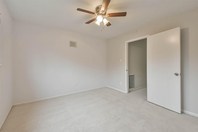 spare room with light carpet, ceiling fan, visible vents, and baseboards