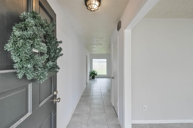 corridor with light tile patterned floors and baseboards