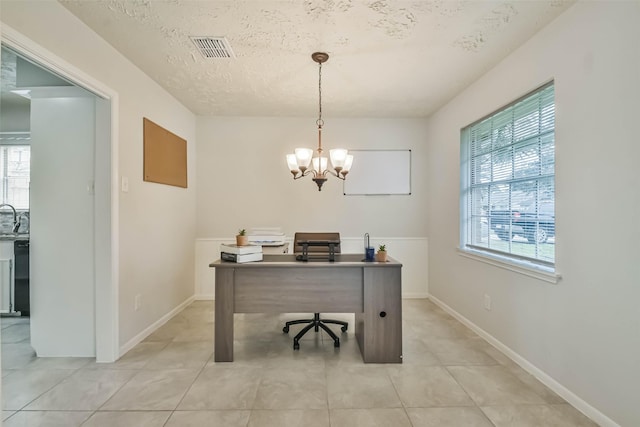 office space with a notable chandelier, a textured ceiling, visible vents, and a healthy amount of sunlight