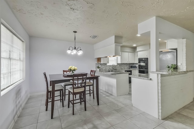 dining area with light tile patterned floors, baseboards, visible vents, a textured ceiling, and a chandelier