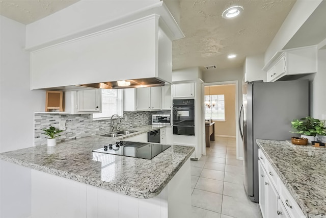 kitchen with white cabinets, stainless steel fridge with ice dispenser, light stone counters, a peninsula, and black electric cooktop