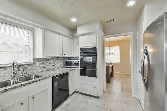 kitchen featuring a sink, white cabinets, black dishwasher, freestanding refrigerator, and a warming drawer