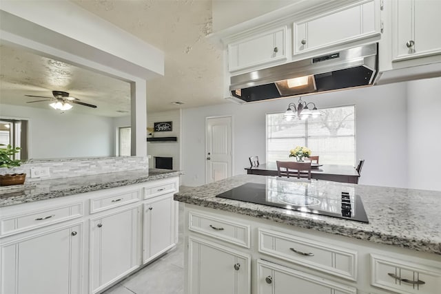 kitchen with a healthy amount of sunlight, under cabinet range hood, white cabinetry, and black electric cooktop