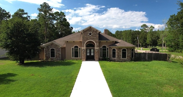 view of front of property featuring stone siding, a chimney, fence, and a front lawn