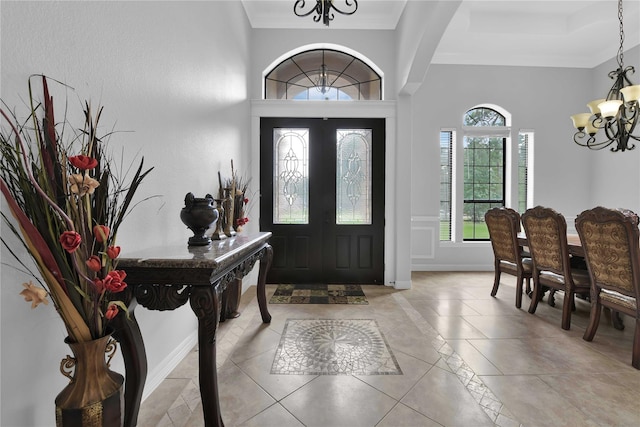 foyer entrance with a chandelier, ornamental molding, and baseboards