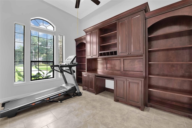 exercise room featuring a healthy amount of sunlight, light tile patterned floors, ceiling fan, and built in study area