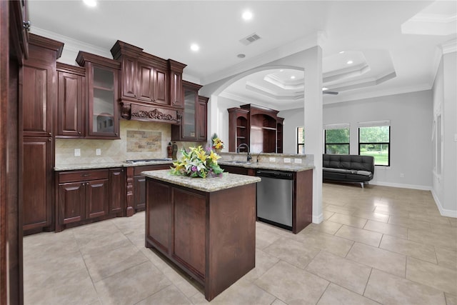 kitchen with stainless steel appliances, ornamental molding, a center island, a raised ceiling, and glass insert cabinets