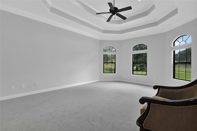 unfurnished room with carpet floors, a tray ceiling, ornamental molding, a ceiling fan, and baseboards