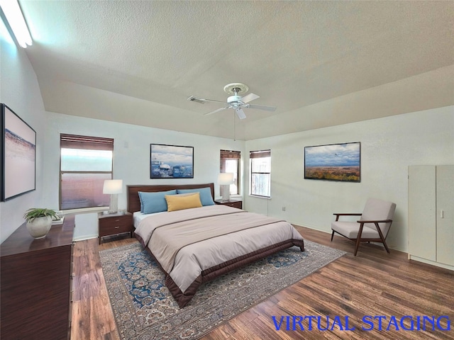 bedroom with a ceiling fan, a textured ceiling, visible vents, and wood finished floors