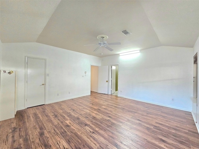 spare room with baseboards, visible vents, ceiling fan, wood finished floors, and vaulted ceiling