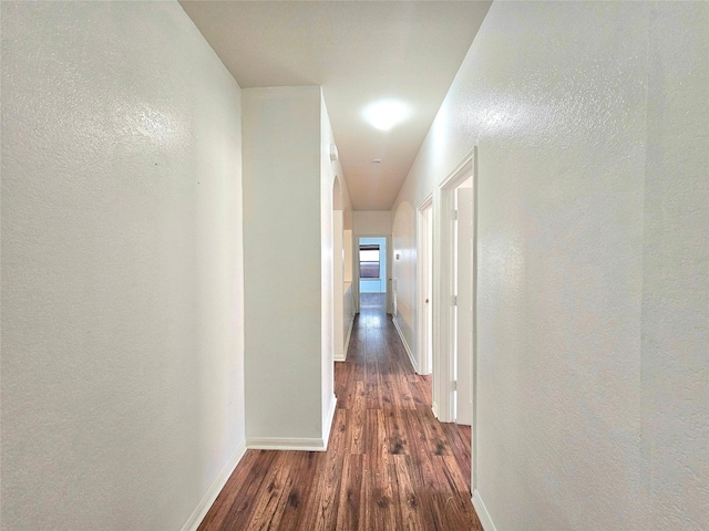 hallway with baseboards, dark wood finished floors, and a textured wall