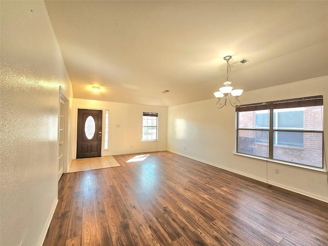 entrance foyer with a chandelier, visible vents, baseboards, and wood finished floors