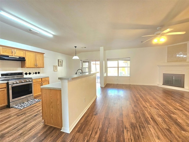 kitchen featuring dark wood-style floors, a glass covered fireplace, stainless steel range with gas stovetop, and under cabinet range hood