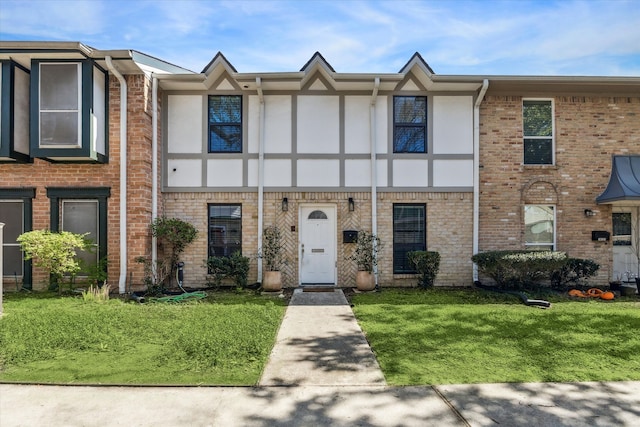 view of property with a front yard, brick siding, and stucco siding