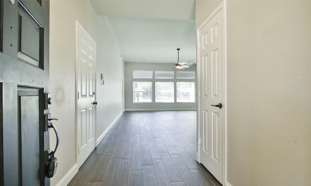 corridor featuring dark wood-style flooring and baseboards