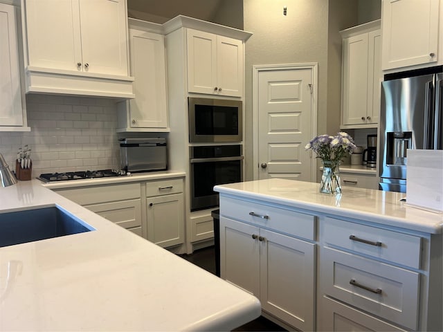 kitchen featuring backsplash, white cabinets, stainless steel appliances, and light countertops