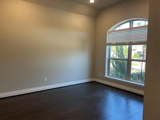 spare room featuring dark wood finished floors, lofted ceiling, recessed lighting, and baseboards