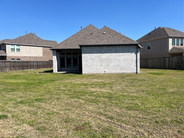 rear view of house featuring brick siding, a lawn, and a fenced backyard