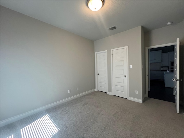 unfurnished bedroom featuring carpet, baseboards, and visible vents