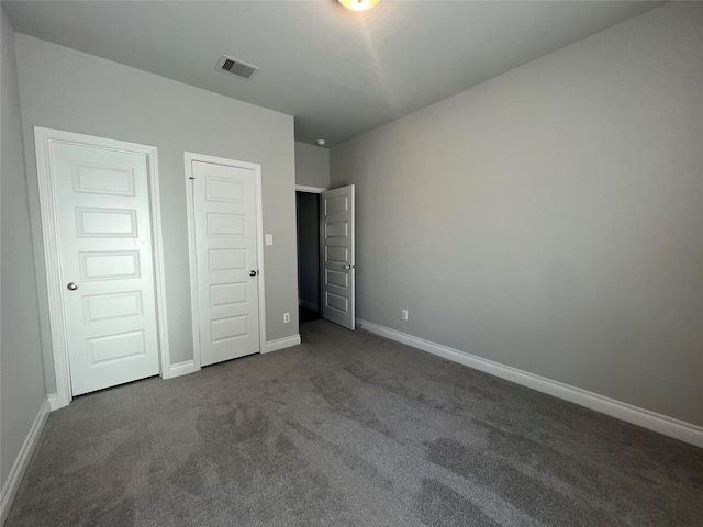 unfurnished bedroom featuring visible vents, baseboards, and dark colored carpet