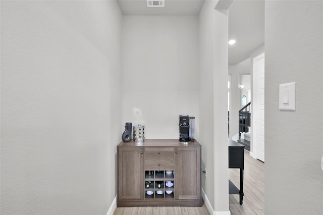 hall featuring visible vents, stairway, baseboards, and wood finished floors