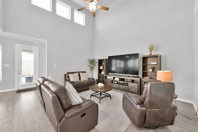 living room with ceiling fan, plenty of natural light, wood finished floors, and baseboards