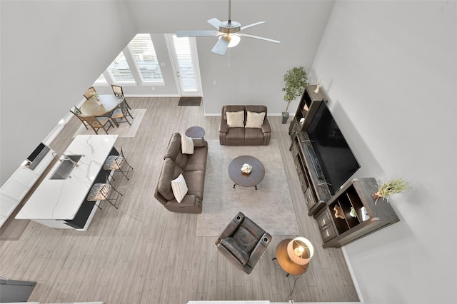 living room featuring baseboards, a ceiling fan, and wood finished floors