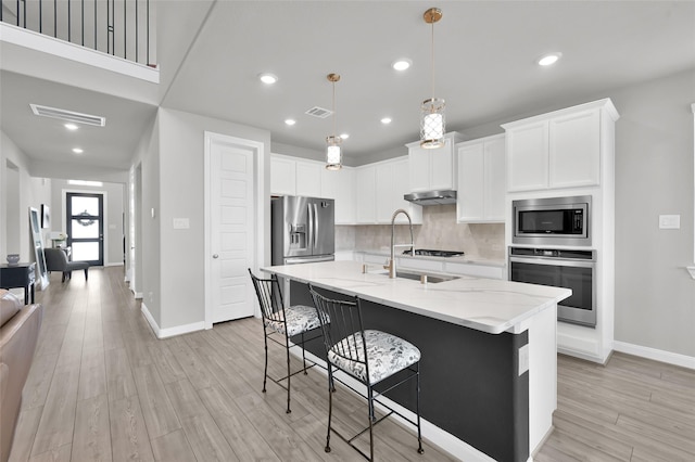 kitchen featuring visible vents, appliances with stainless steel finishes, decorative backsplash, and light stone counters