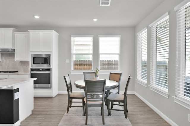 dining area with light wood finished floors, baseboards, visible vents, and recessed lighting