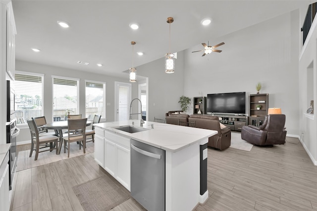 kitchen with white cabinets, dishwasher, light wood finished floors, and a sink