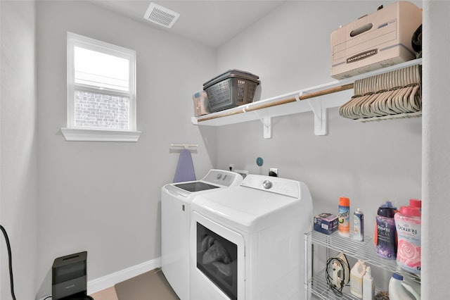 clothes washing area with laundry area, visible vents, baseboards, and washing machine and clothes dryer