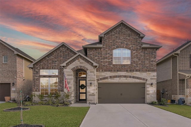 french provincial home featuring brick siding, concrete driveway, stone siding, an attached garage, and a front yard