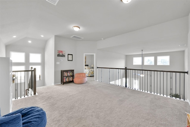 sitting room with carpet, plenty of natural light, lofted ceiling, and visible vents