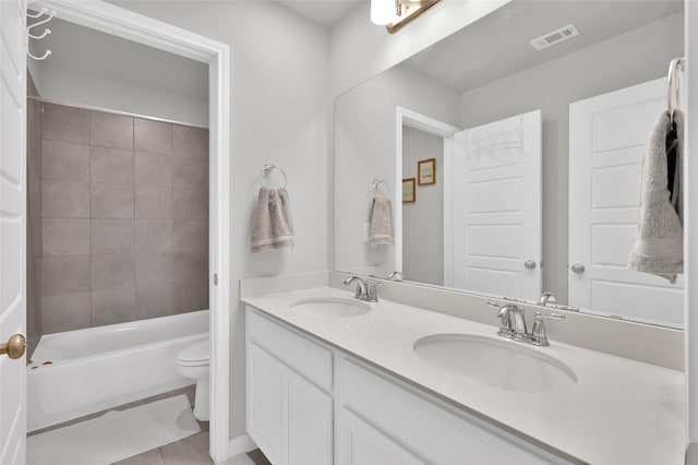 bathroom with visible vents, double vanity, a sink, and toilet