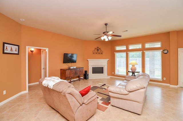 living room featuring light tile patterned floors, a fireplace with raised hearth, visible vents, a ceiling fan, and baseboards