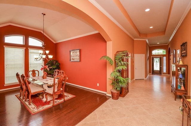 dining room with arched walkways, ornamental molding, vaulted ceiling, a chandelier, and baseboards