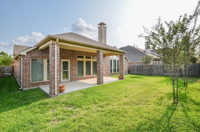 rear view of house with a fenced backyard, a patio, and brick siding