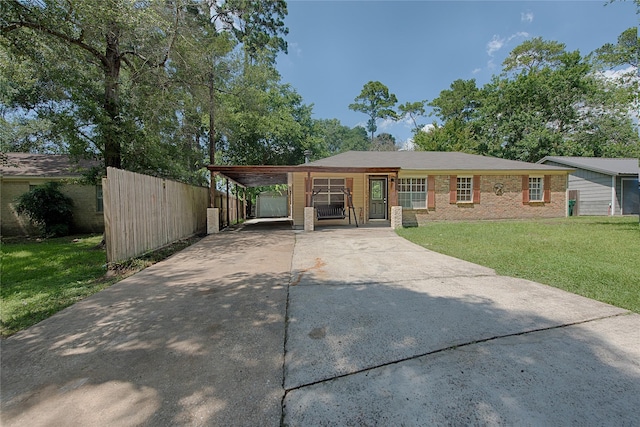 view of front of house with an attached carport, brick siding, fence, driveway, and a front yard