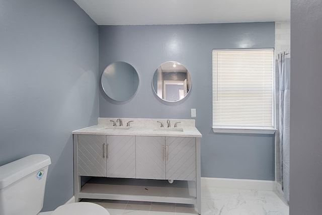 bathroom featuring marble finish floor, baseboards, a sink, and toilet