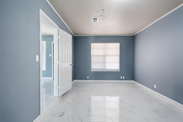 spare room with marble finish floor, visible vents, baseboards, and a textured ceiling