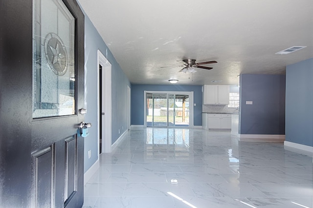 unfurnished living room featuring marble finish floor, visible vents, ceiling fan, and baseboards